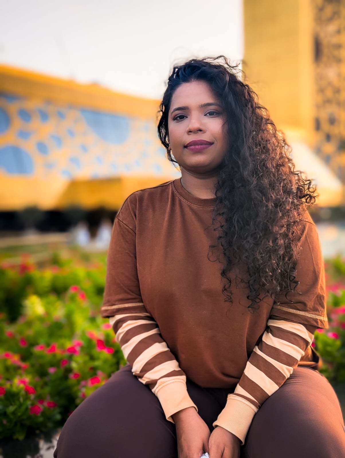 Hurrain Sheikh, a facilitator with long curly hair, seated outdoors